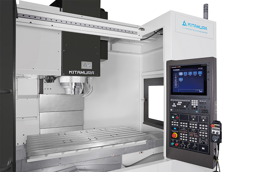 Close-up of a Kitamura vertical machining center with an advanced CNC control panel and a large, empty worktable ready for operation.