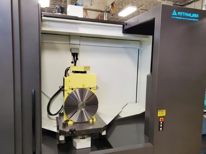 Kitamura CNC machine with a rotary table and a yellow workholding fixture.