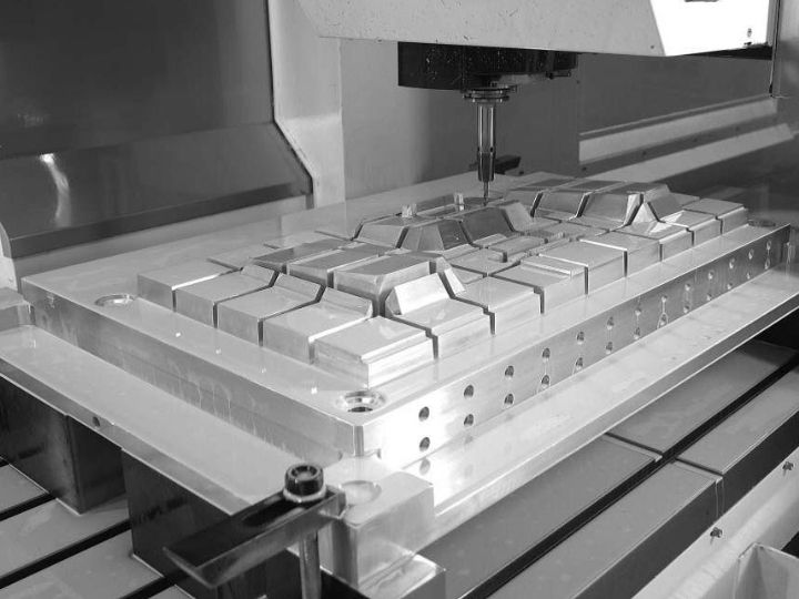 CNC machine performing precision milling on a metal mold.