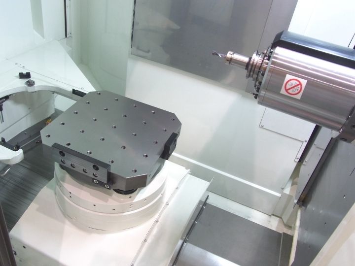 CNC machine workspace with a rotary table and spindle equipped with a cutting tool.