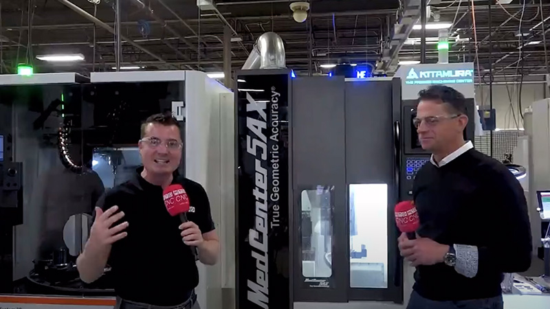 Two people in front of cnc industrial machine.