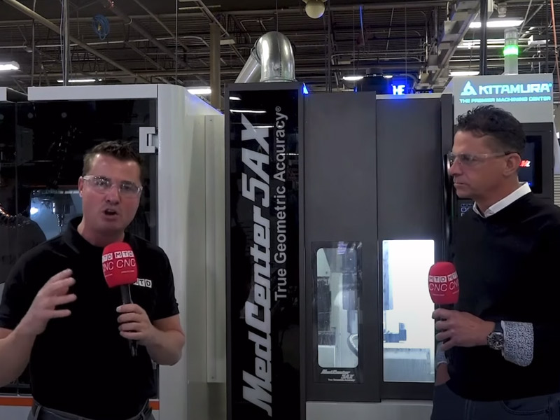 Two people holding microphones and conducting an interview about manufacturing machines.