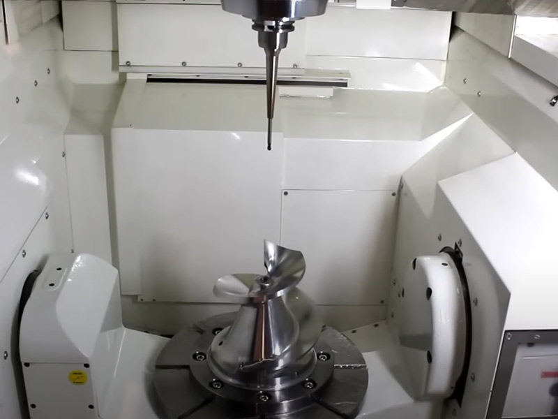 The inside of a manufacturing machine with a drill coming from the top of the machine.