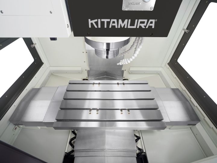 Kitamura CNC machine workspace with a vertical spindle and metal worktable.