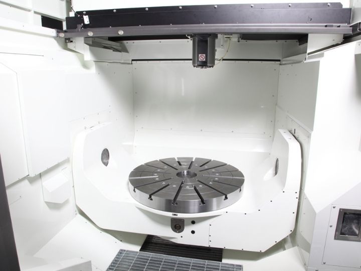 Interior view of a Kitamura Mytrunnion-7G CNC machine, showcasing a large rotary table for precision machining operations.