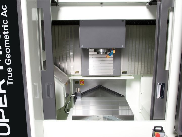 Enclosed CNC machine workspace with a vertical spindle and metal worktable.