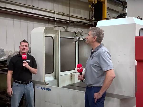 Two people in front of cnc machine.