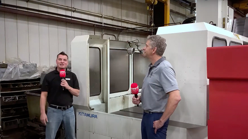 Two people in front of cnc machine.