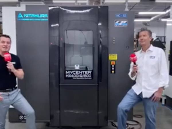 Two people talking in front of a industrial machine.