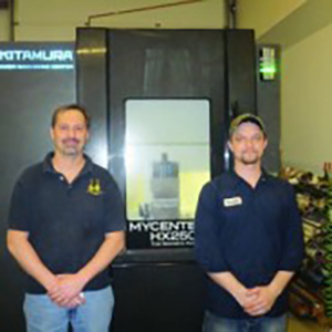 Two people standing next to a manufacturing machine.