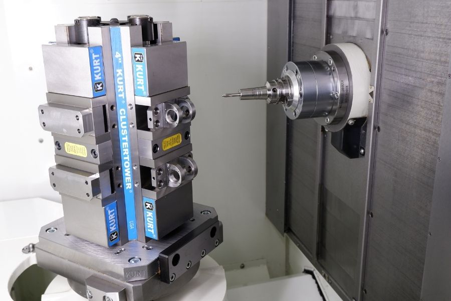 Horizontal machining center setup showing a Kurt ClusterTower vise fixture holding multiple parts, aligned with a precision cutting spindle.