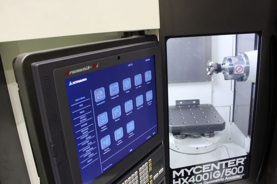 Close-up of a Kitamura MYCENTER HX400iG/500 horizontal machining center showing the control interface and interior workspace with a rotary table.