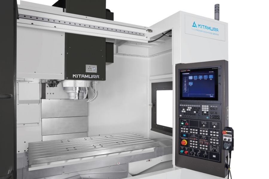 Interior of a Kitamura vertical machining center showing the large worktable, spindle head, and touchscreen CNC control panel for precise operations.
