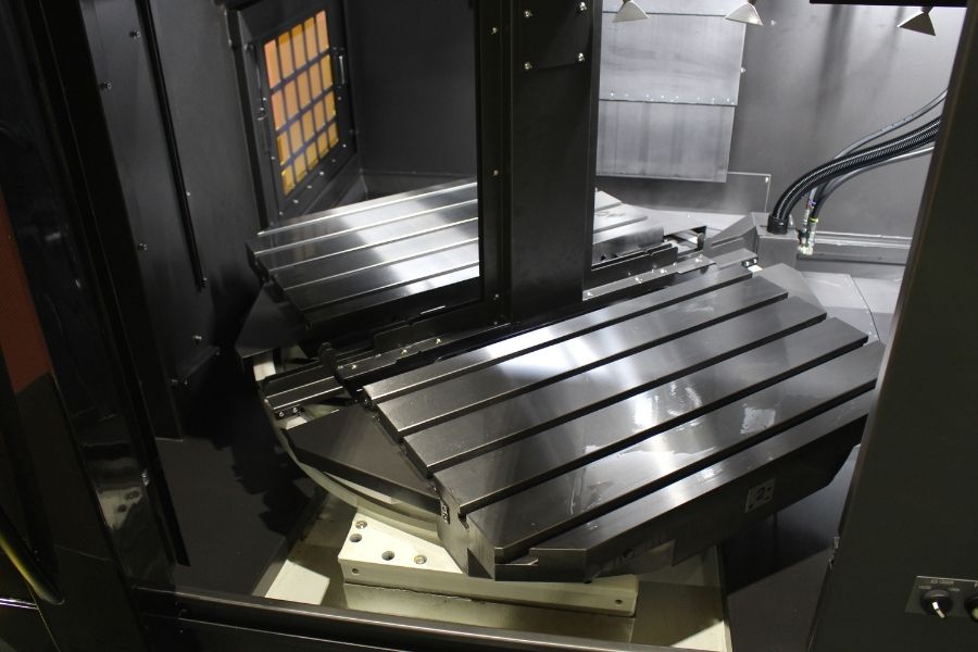 Interior view of a high-precision vertical machining center featuring dual tilting worktables designed for multi-axis simultaneous machining.